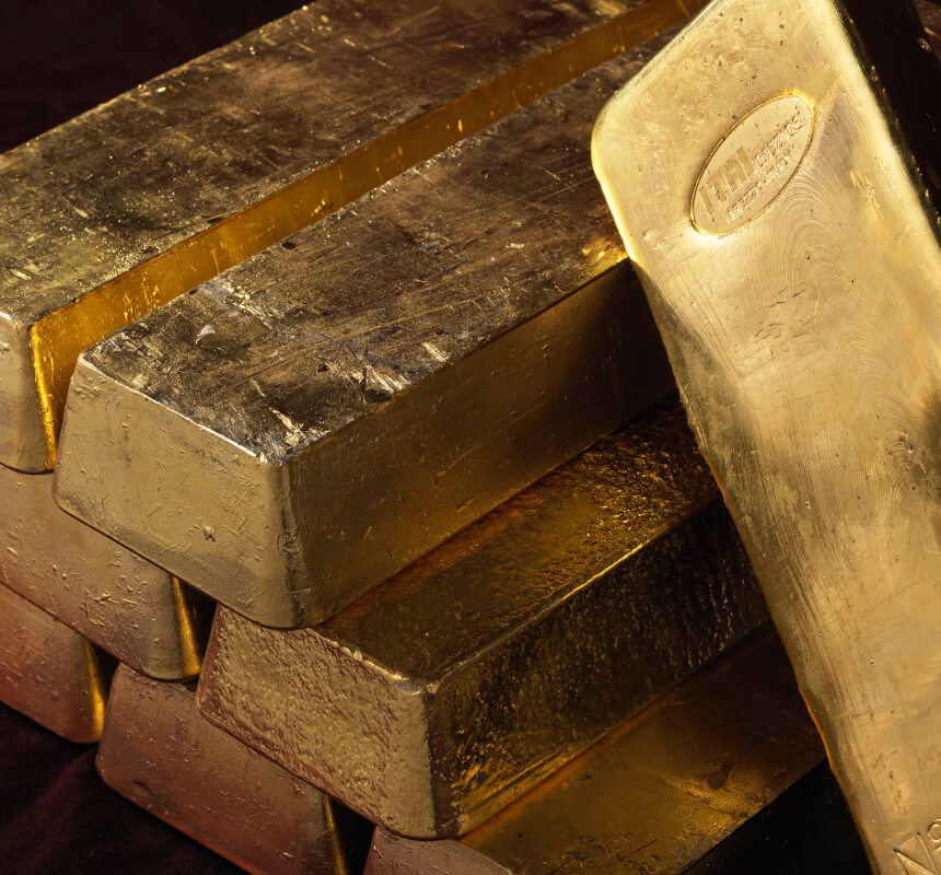 Lingotti d'oro impilati che mostrano una superficie lucida e metallica e una struttura visibile.