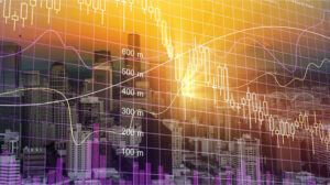 Immagine concettuale che rappresenta mercati finanziari e investimenti: skyline urbano sfumato in arancione e viola con sovrapposizione di grafici azionari, candlestick e linee di andamento dei prezzi.